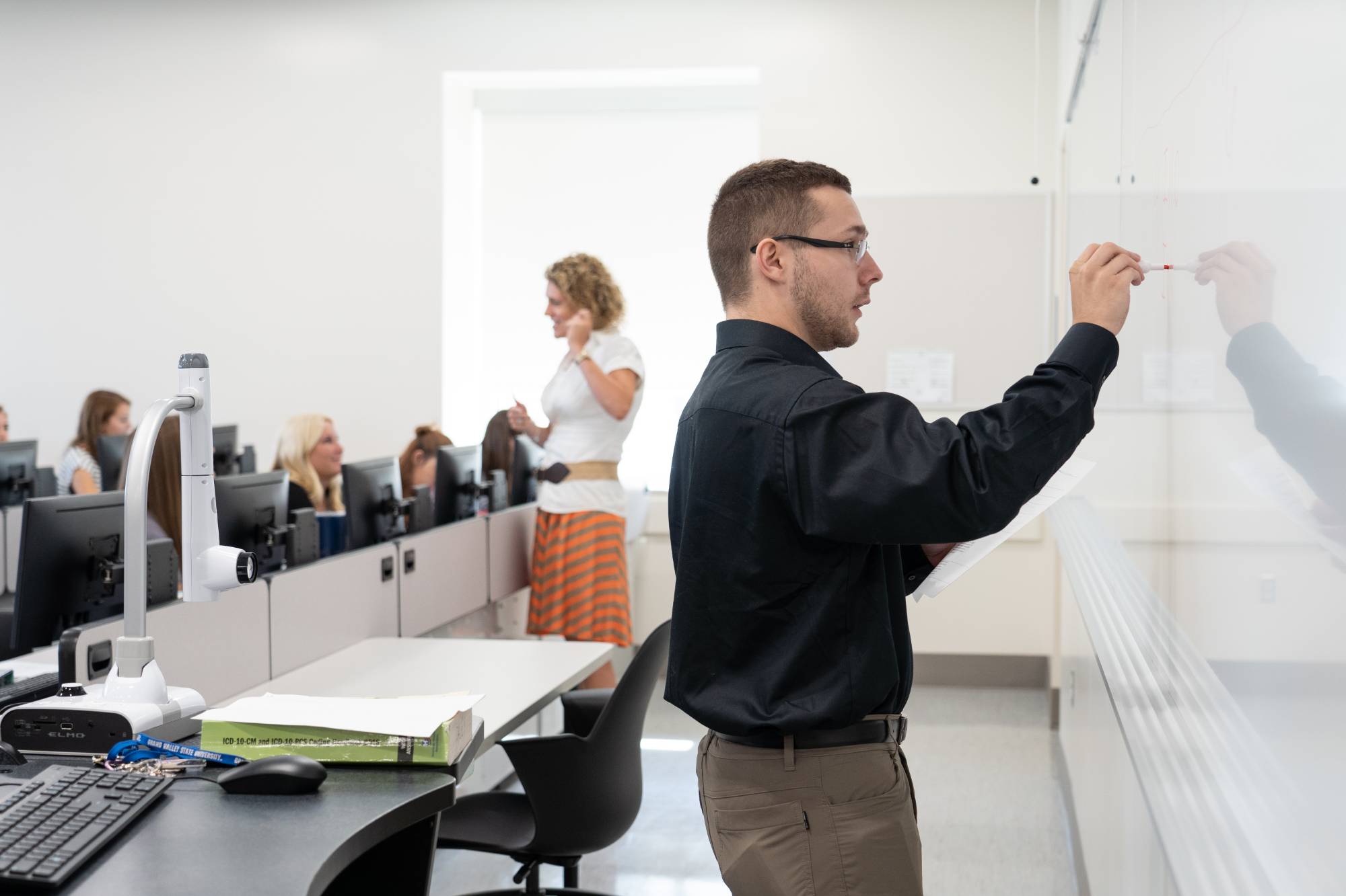 Instructor teaching up at the whiteboard of a classroom